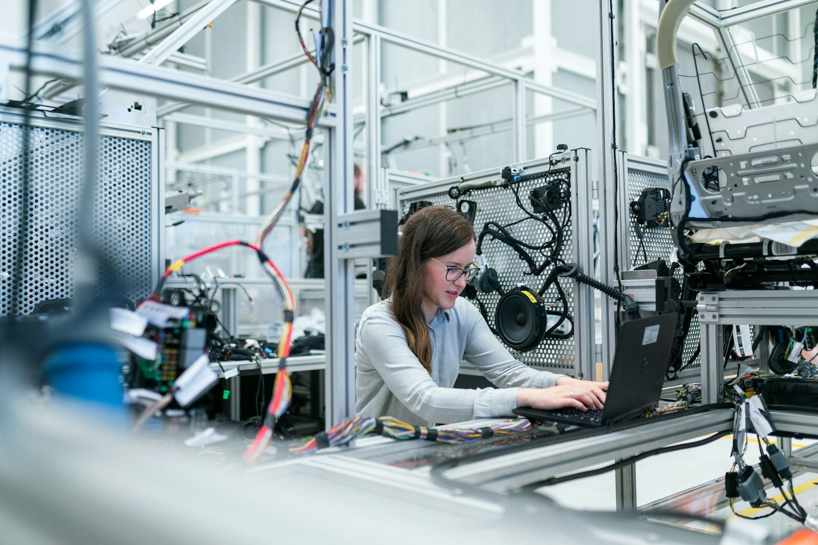 An engineer at a laptop beside a line of connected equipment.